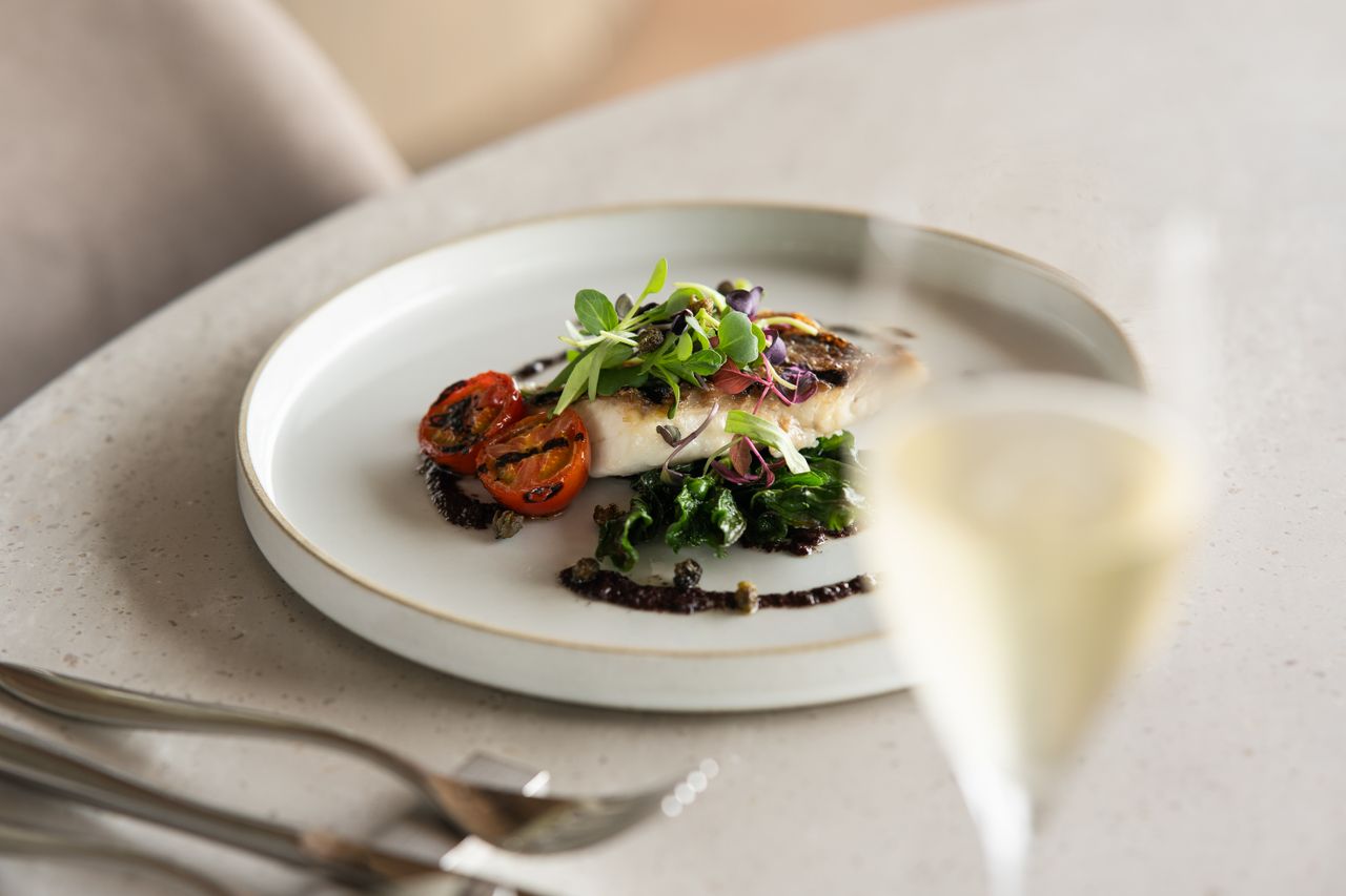 A gourmet dish featuring fish fillet with grilled vegetables, captured elegantly at a Tokyo restaurant.